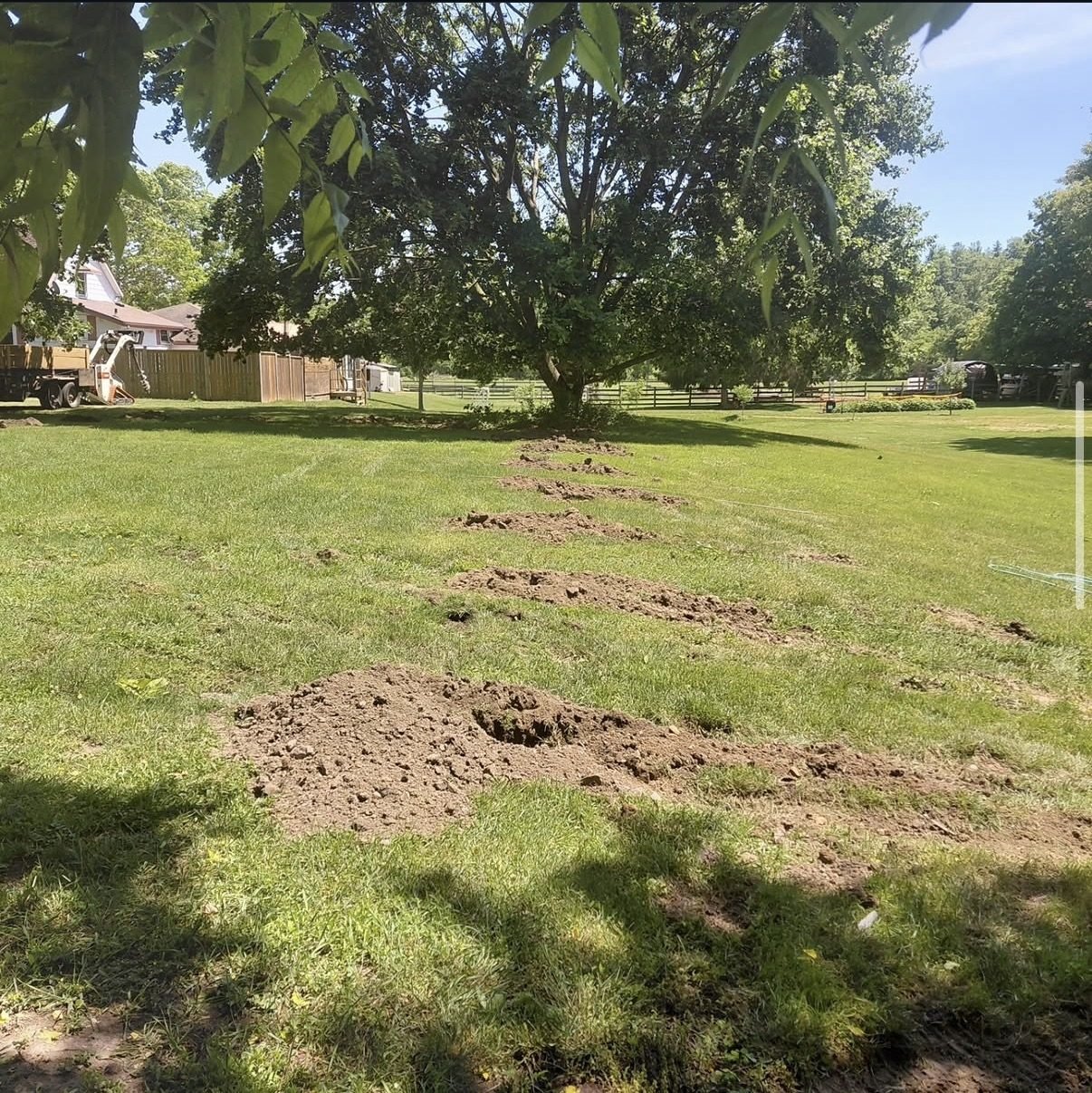 Auger and skid steer equipment setting fence posts on a job site