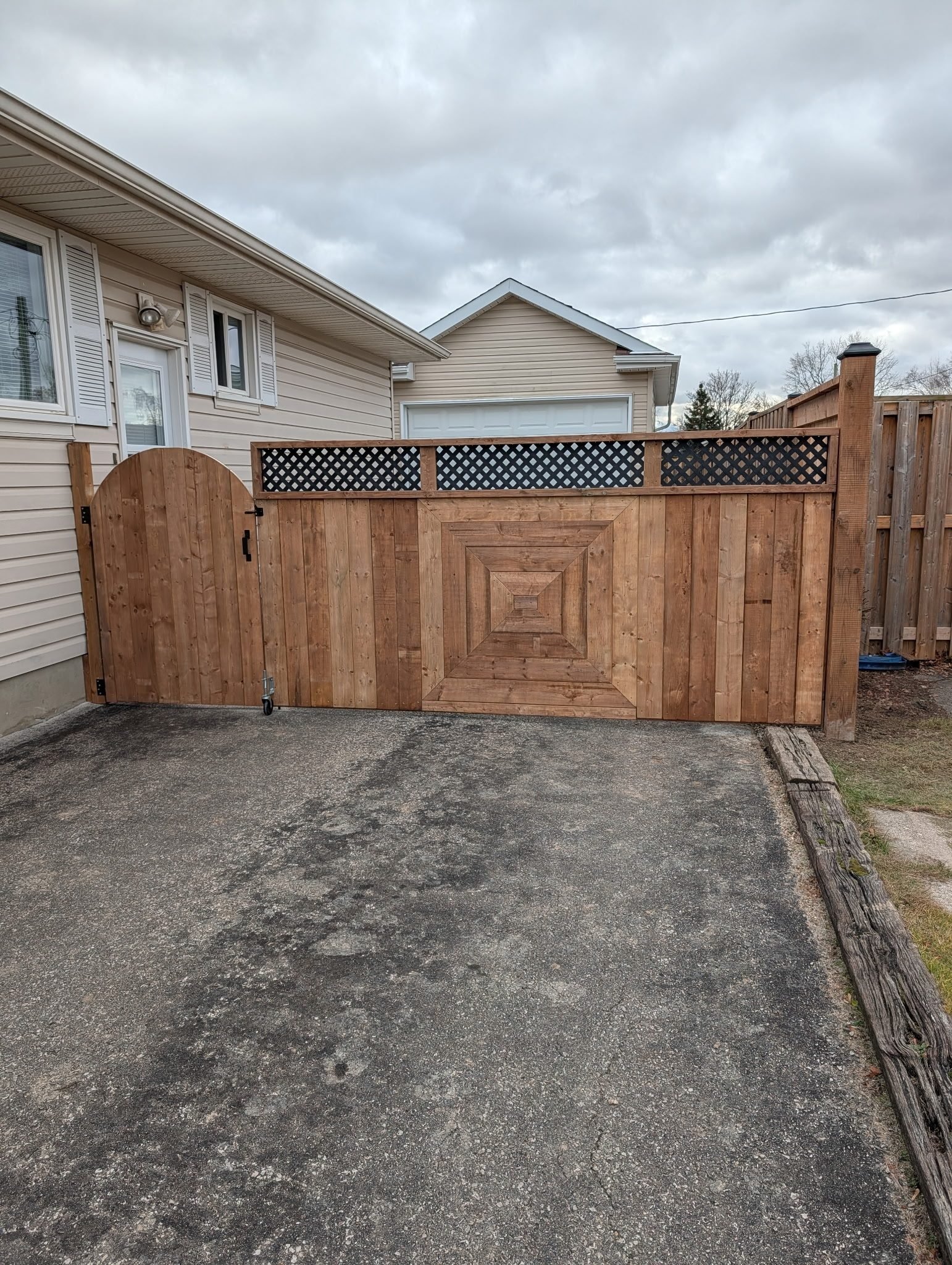 Large custom wood gate with a diamond panel design and lattice top