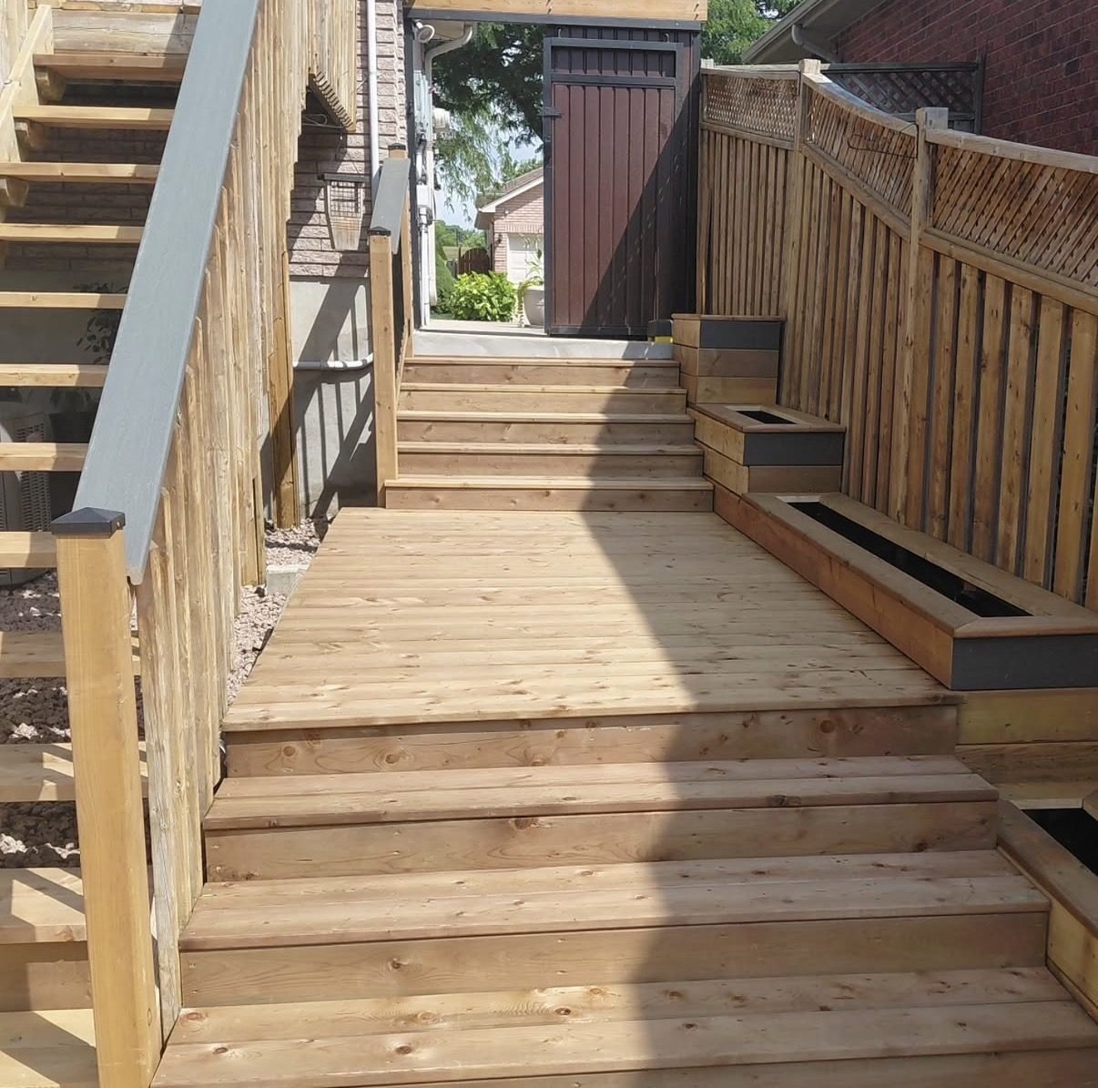 Wood deck staircase with composite railing leading to a backyard