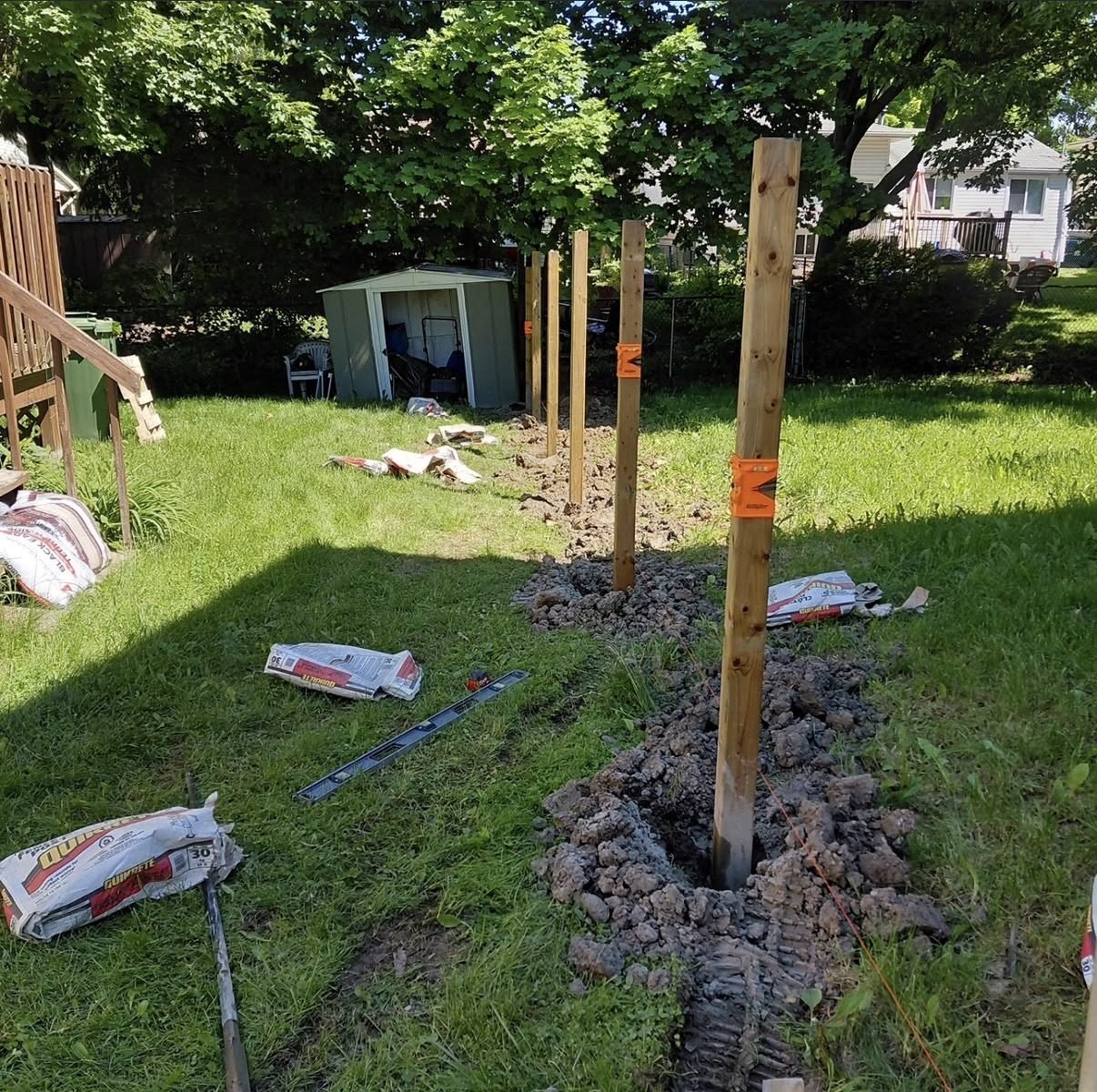 Fresh post holes dug and lined up along a lawn ready for repair