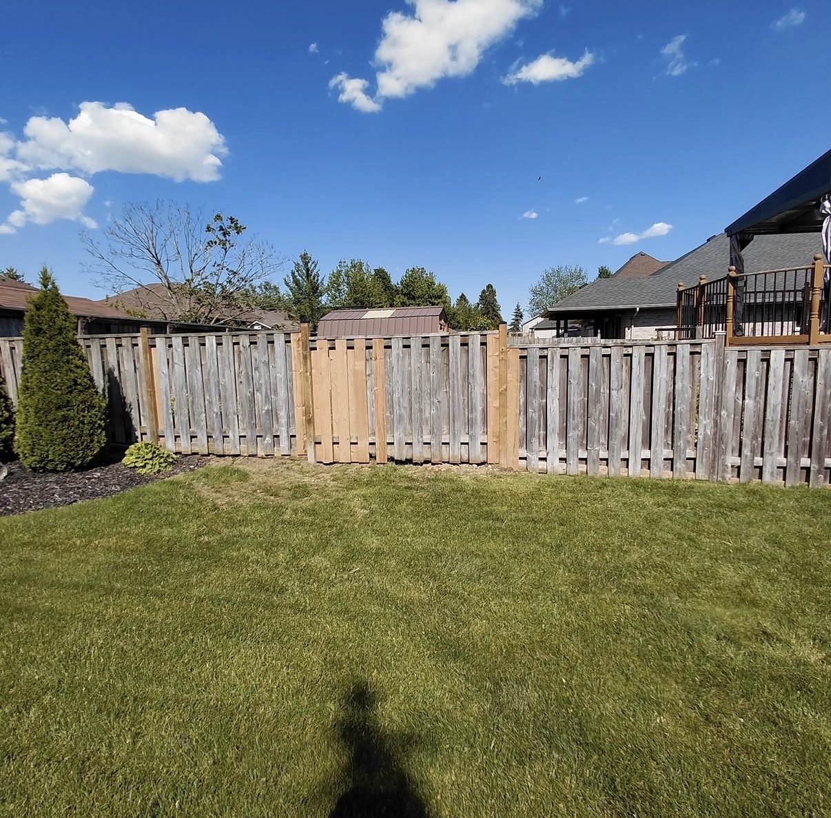Weathered wood fence with a new section of boards spliced in to match