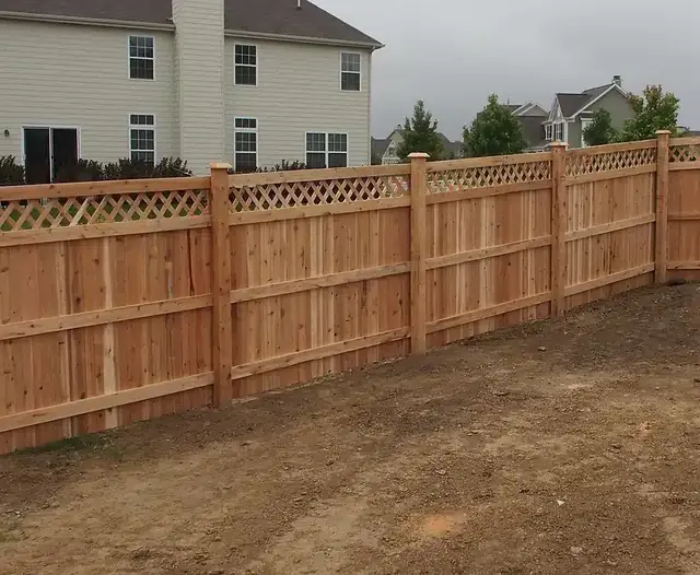 Wood privacy fence with a framed lattice top along a backyard