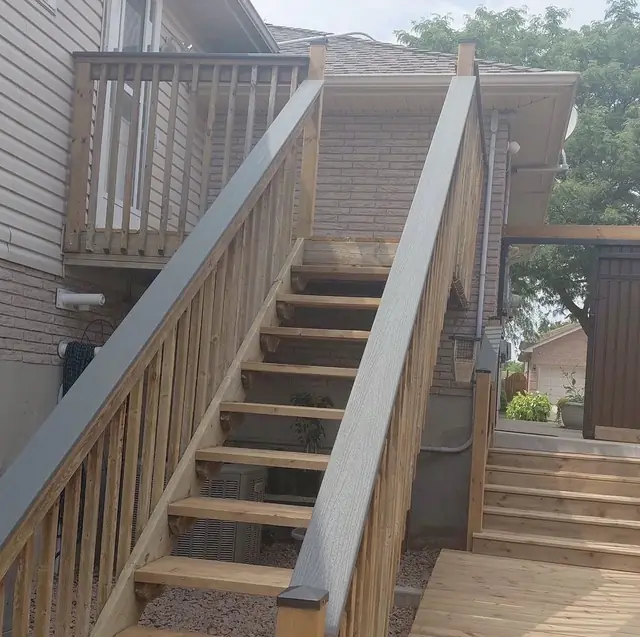 Raised wood deck with a long staircase and grey railing